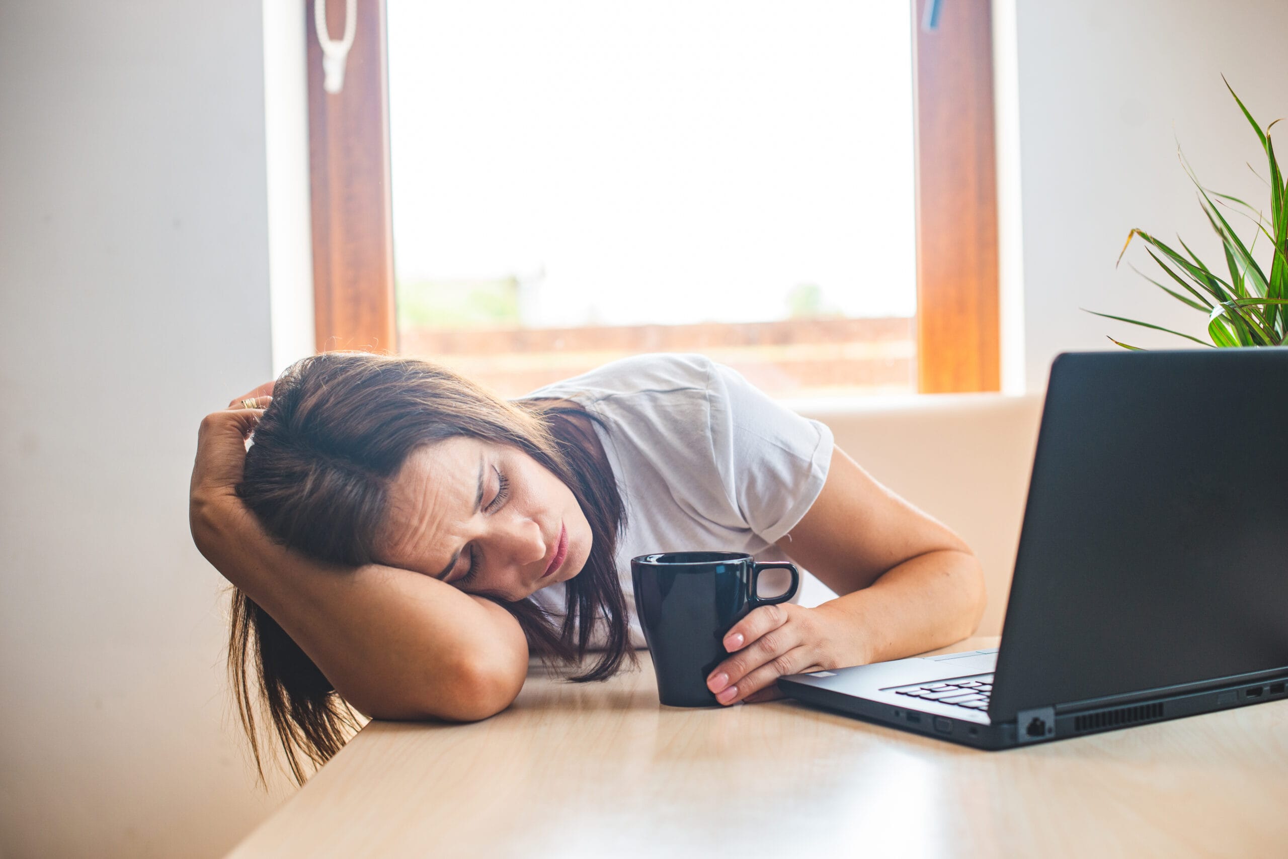 Tired businesswoman sleeping on table in office. Young exhausted birth trauma