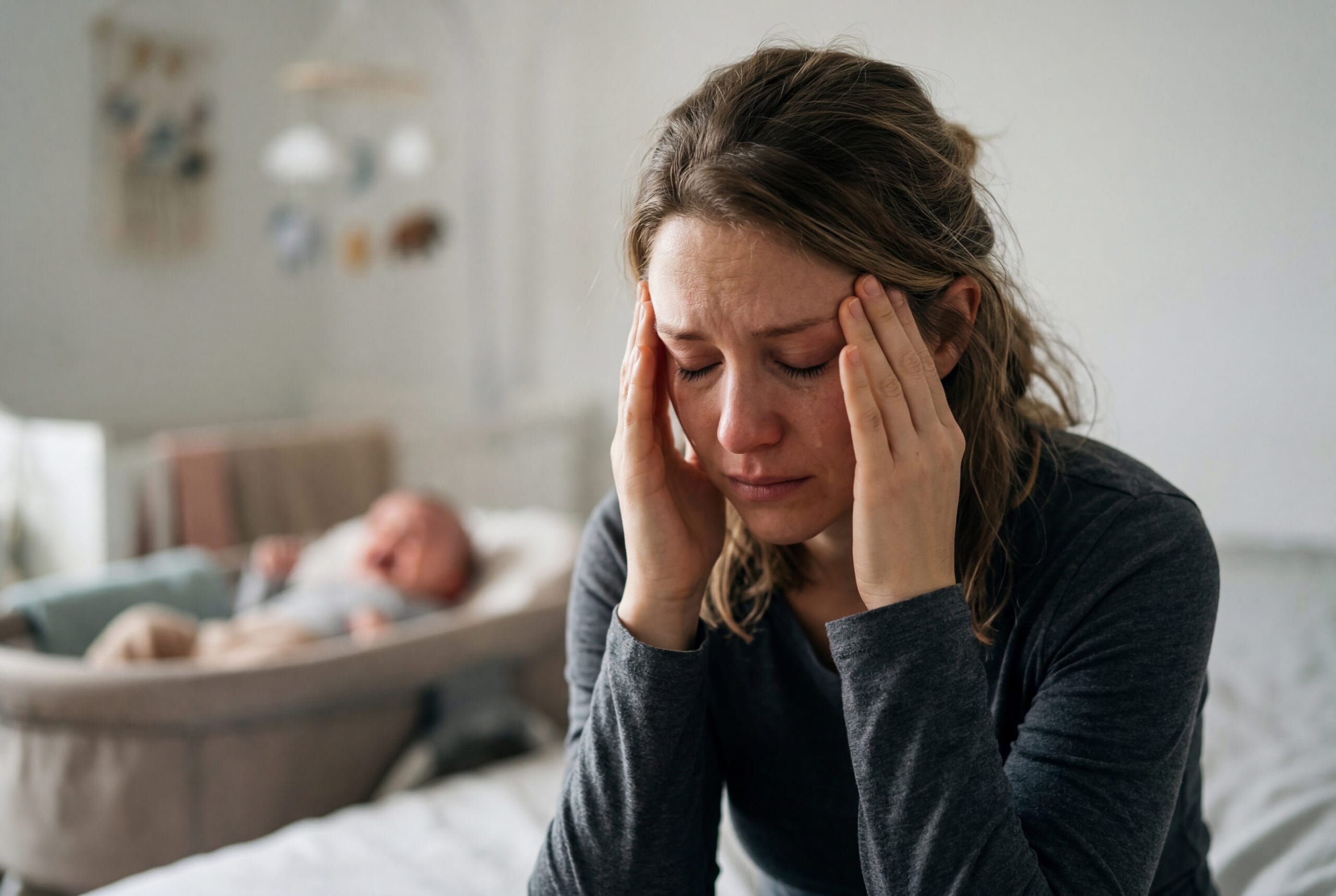 Exhausted mother suffering from postpartum depression sitting with baby birth trauma